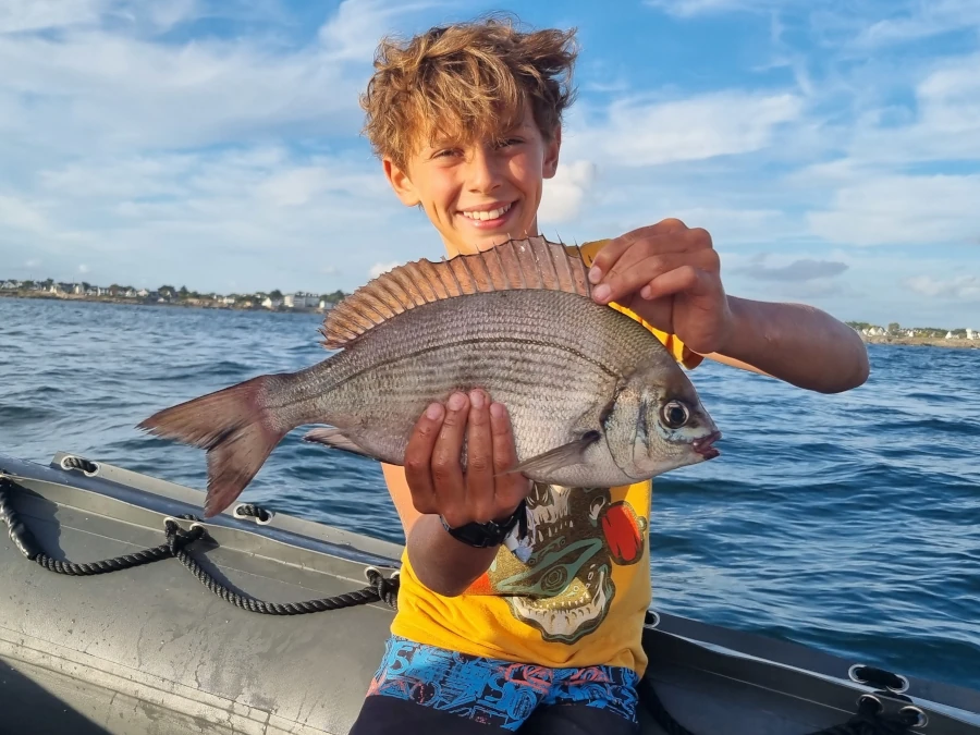 Enfant sur un bateau en pêche en mer, avec une énorme dorade grise à l' ile de Ré
